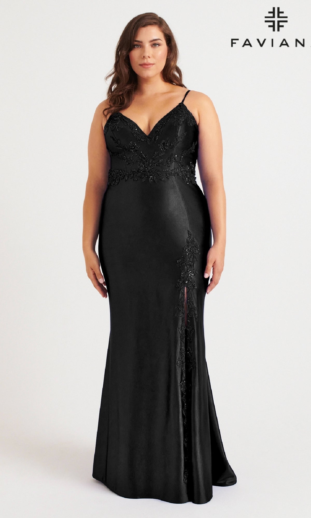 A woman models the Faviana 9562, a long plus-size black prom dress with a beaded bodice and lace details, standing against a white background with the